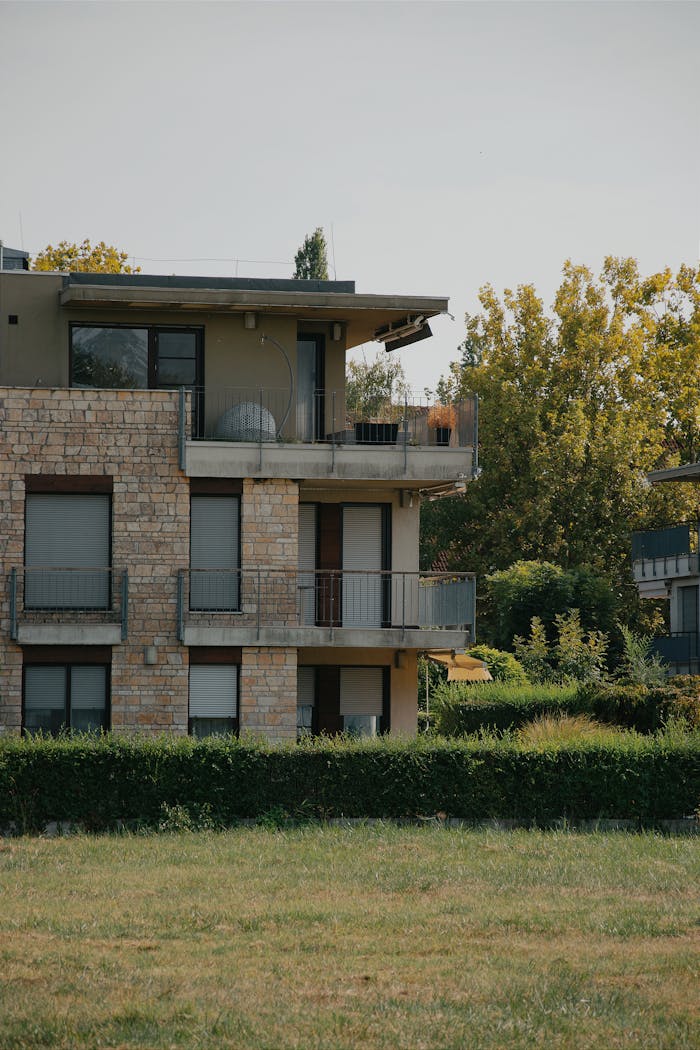 Modern Hungarian apartment building with stone facade and lush greenery on a summer day.