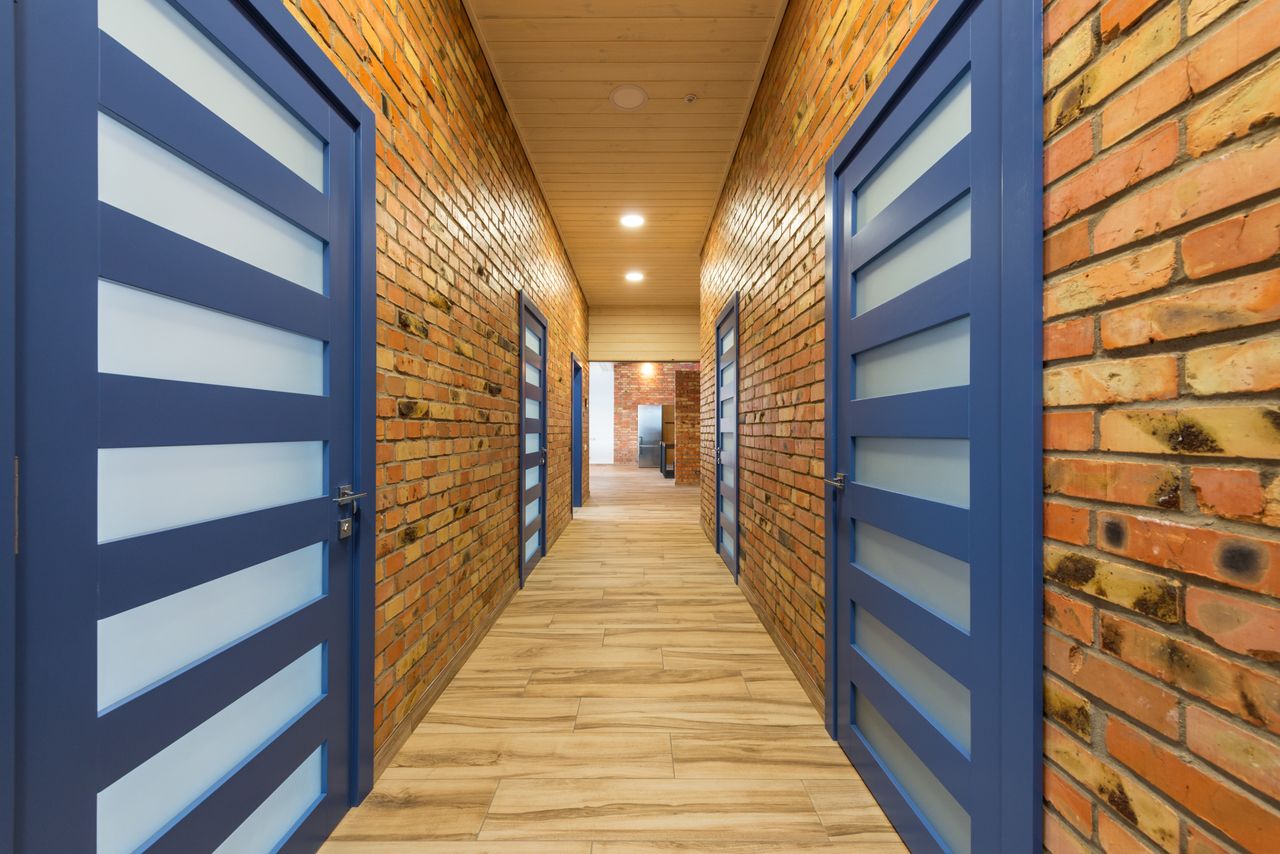 Bright hallway with brick walls and striking blue doors creating a modern atmosphere.